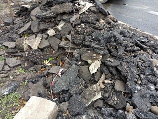The old asphalt removed from the road for replacement is piled in the yard.