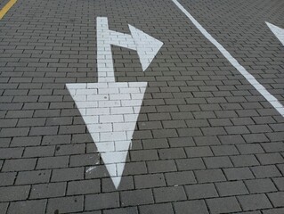 Road markings on a cobblestone road. Arrows for traffic in the parking lot. White paint marking on...