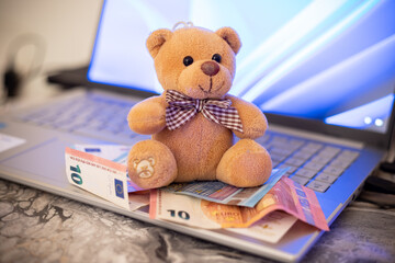 Toy bear and banknotes on laptop keyboard. Purchasing goods online