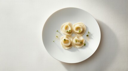  a white plate topped with ravioli and garnished with green garnish on top of a white table.