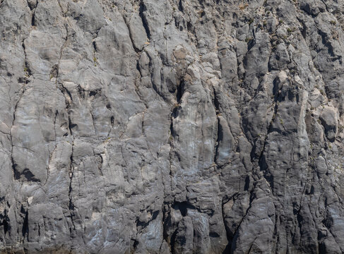 Weathered seaside rock face texture . Aged volcanic stone wall surface background pattern with cracks and scratches. Ischia Island, Italy.