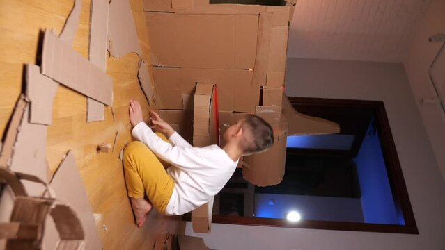 vertical video boy builds a spaceship out of cardboard