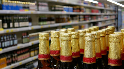 Close-up of many golden foiled beer bottles in a beer department