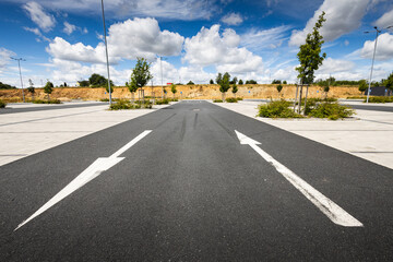 Empty asphalt road with white arrows and clouds on blue sky on background - obrazy, fototapety, plakaty