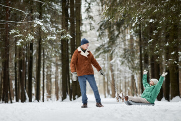 Naklejka premium Joyful senior couple spending together in winter forest