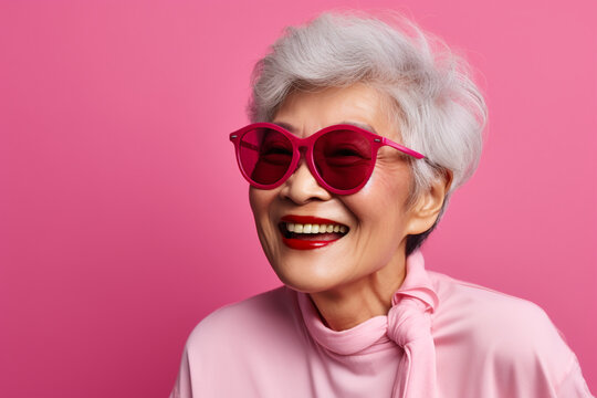 Portrait of a smiling happy asian woman with gray hair over pink background. . High quality photo