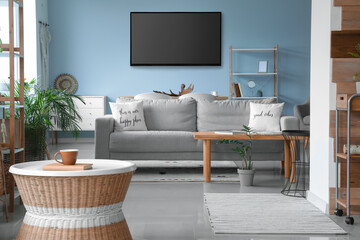 Modern smart TV set hanging on blue wall in living room - obrazy, fototapety, plakaty