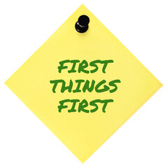First Things First reminder green marker motivational text, important crucial business action concept, large isolated yellow post-it sticky adhesive note sticker, black pushpin thumbtack macro closeup - 683968534