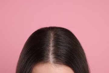Woman with healthy dark hair on pink background, closeup