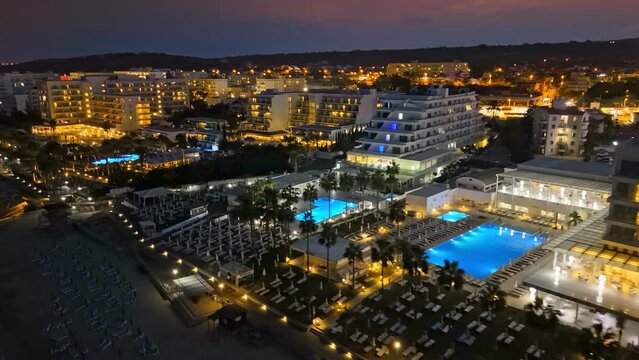 Aerial night view of luxury hotels and resorts in Protaras, Cyprus. Beachfront resorts on Mediterranean Sea. Nightlife in summer Cyprus 