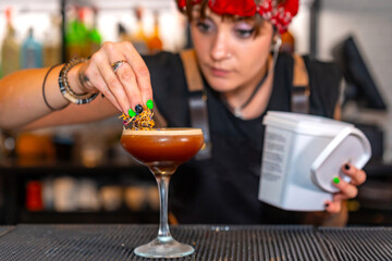 Accurate young bartender garnishing a cocktail glass