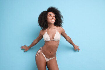 Beautiful woman in stylish bikini on light blue background