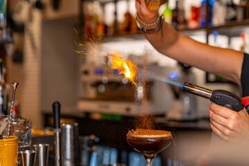 Bartender burning the topping of a cocktail using torch