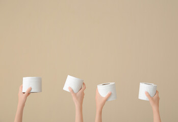 Female hands with toilet paper rolls against color background