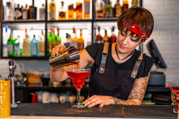 Professional young bartender preparing a red cocktail in the bar