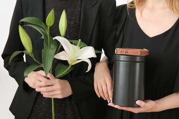 Women with mortuary urn, dog collar and lily flowers, closeup. Pet funeral