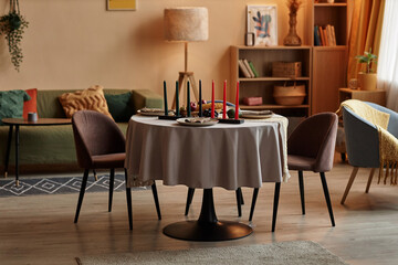 Colorful candles and bowl with fruits and vegetables on round table prepared for family Kwanzaa celebration