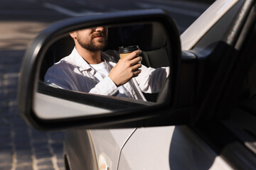 Coffee to go. Man with paper cup of drink, view through car side mirror