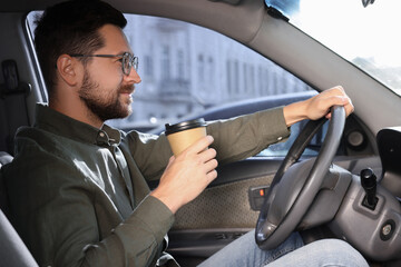 Coffee to go. Handsome man with paper cup of drink driving his car