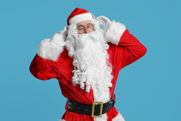 Merry Christmas. Santa Claus in headphones listening to music on light blue background
