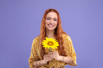 Beautiful young hippie woman with sunflower on violet background