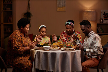 Parents and kids gathered around table, praying together as they share meal