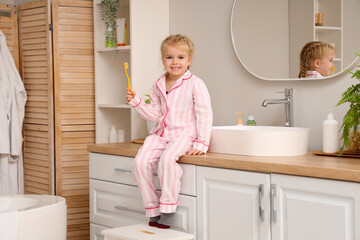 Cute little girl with toothbrush in bathroom