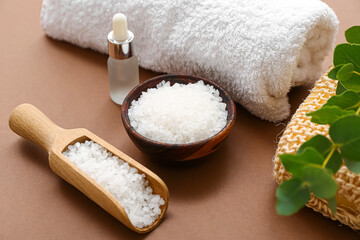 Bowl of sea salt, essential oil and bath supplies on color background, closeup