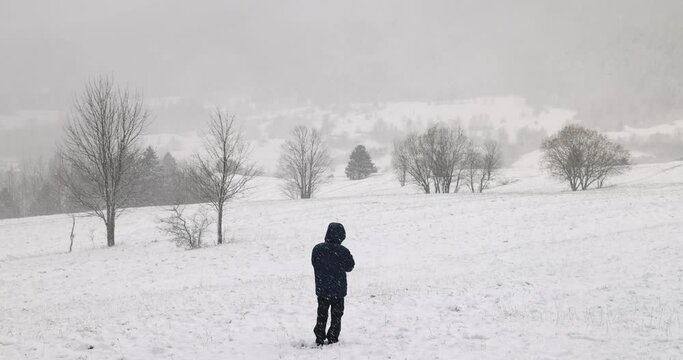 A man standing in winter hazy landscape at snowfall. Slow motion 4k 100fps.