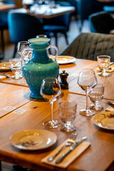 Wooden table in the restaurant with plates, wine glasses and cutlery