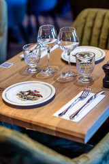 Wooden table in the restaurant with plates, wine glasses and cutlery