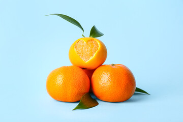 Sweet mandarins with leaves on blue background