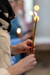 Obraz na płótnie Canvas Burning candles in the hands of a woman in the Orthodox church