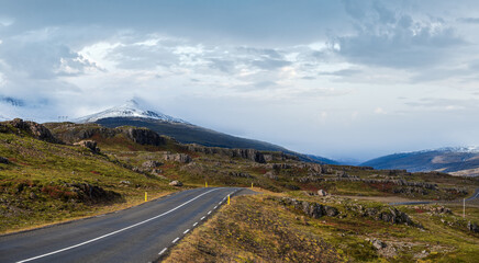 Highway road and mountain view during auto trip in Iceland. Spectacular Icelandic landscape with  scenic nature: fjords, fields, clouds, glaciers, waterfalls.