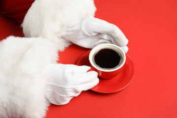Obraz na płótnie Canvas Santa Claus hands with cup of aromatic coffee on red background, closeup