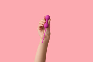 Female hand with vaginal balls on pink background, closeup