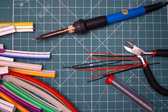 Soldering wires on the table.A hot soldering iron with wires is lying on the table.