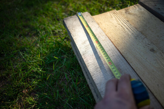 Measuring boards for construction with a long tape measure.Suburban construction in the fresh air.Building a house with your own hands.