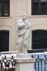 A snow-covered stone sculpture of a supposed Christian apostle holding a book stands outside the...