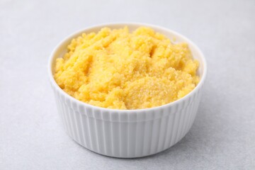 Tasty cornmeal in bowl on light gray table, closeup