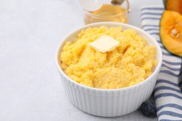 Tasty cornmeal with butter in bowl on table, closeup