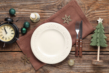 Beautiful table setting for Christmas dinner with alarm clock and decorations on wooden background