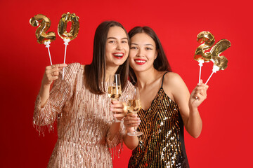Beautiful young women with champagne and figure 2024 on red background. New Year celebration