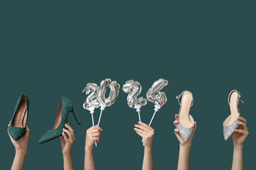 Female hands with high heel shoes and figure 2024 made of balloons on dark green background