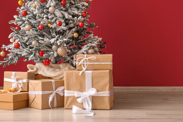 Decorated Christmas tree with presents near color wall, closeup