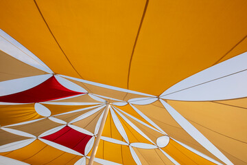 Colourfully Sun Tent on Blue Sky. Yellow, Orange and Red Shade Sails Pattern.