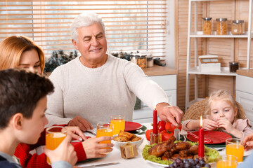 Happy mature man having Christmas dinner with his family in kitchen