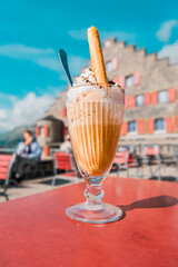 Glass of milkshake with whipped cream on a table in a cafe