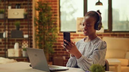 Woman using smartphone videocall at home, briefing contractor about freelance work progress before...