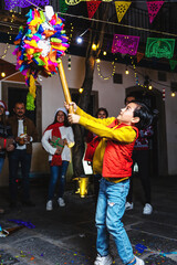 Latin family breaking a pinata at traditional mexican posada celebration for Christmas eve in...